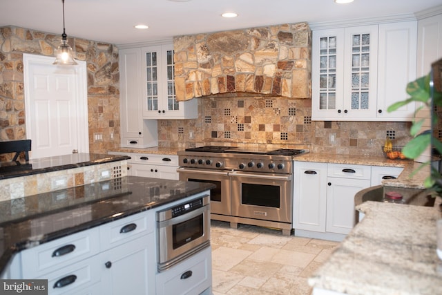 kitchen with double oven range, light stone countertops, and white cabinets