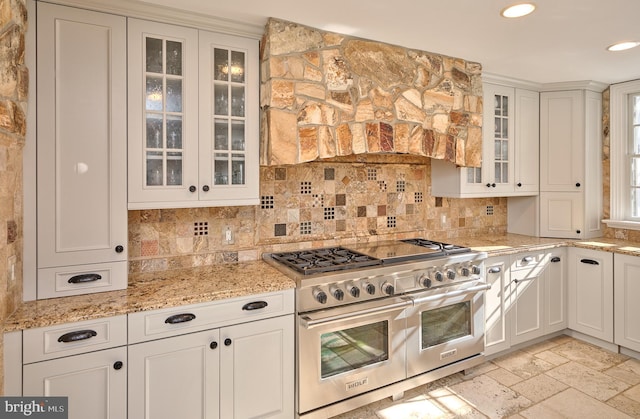 kitchen featuring double oven range, light stone countertops, and white cabinets