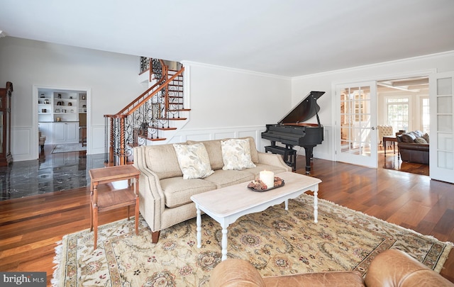 living room featuring dark hardwood / wood-style flooring, built in shelves, ornamental molding, and french doors