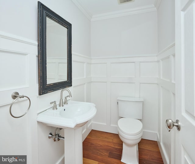 bathroom with crown molding, hardwood / wood-style floors, and toilet