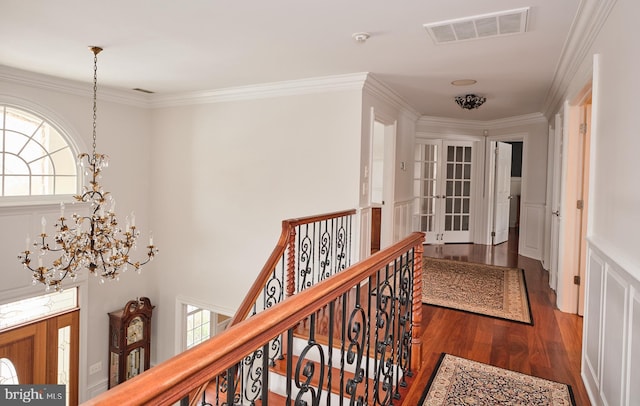 corridor featuring wood-type flooring, ornamental molding, and a chandelier