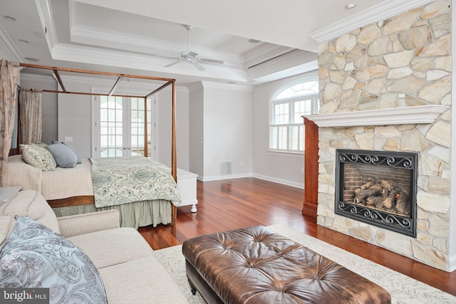 bedroom featuring ornamental molding, dark wood-type flooring, a fireplace, and a tray ceiling