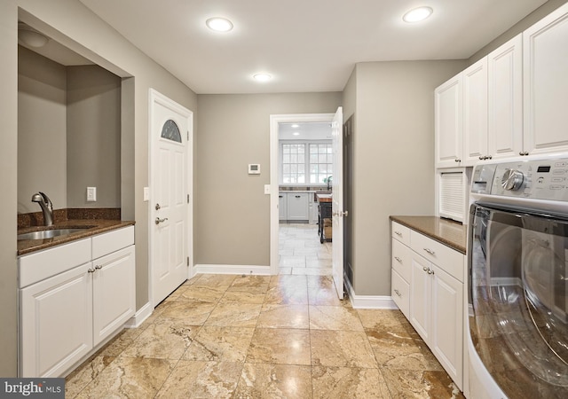 clothes washing area featuring cabinets, washer / dryer, and sink