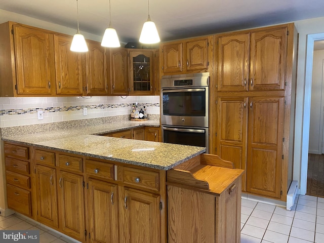 kitchen with tasteful backsplash, light tile patterned floors, light stone countertops, and stainless steel double oven