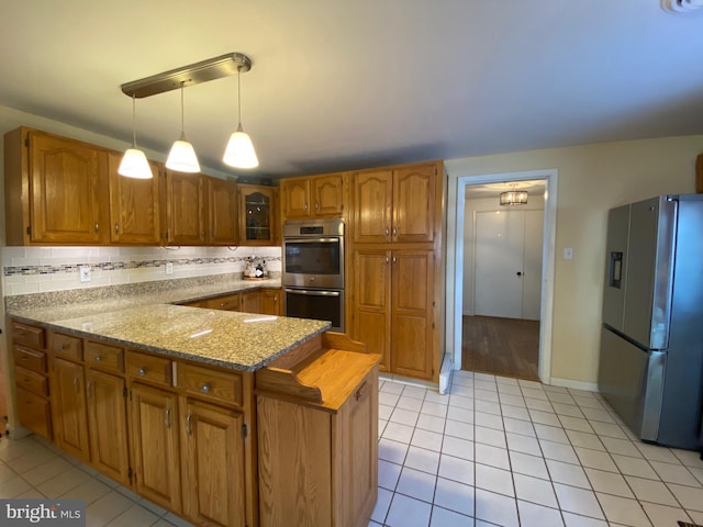 kitchen featuring light tile patterned floors, hanging light fixtures, backsplash, stainless steel appliances, and light stone countertops