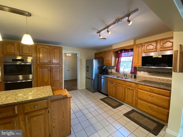 kitchen with sink, dark stone counters, light tile patterned floors, pendant lighting, and stainless steel appliances