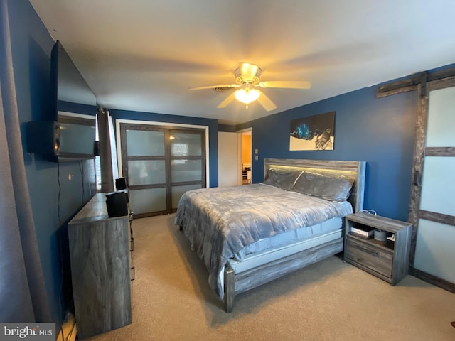 carpeted bedroom featuring a barn door and ceiling fan