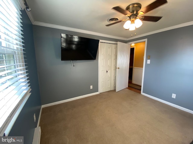 unfurnished bedroom with multiple windows, ornamental molding, ceiling fan, and a closet