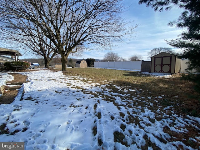 snowy yard featuring a shed