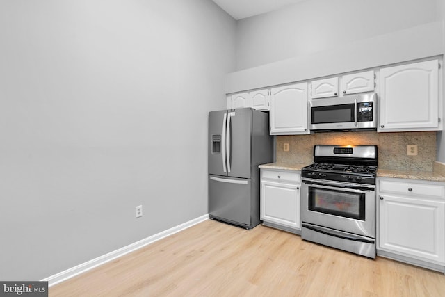 kitchen featuring white cabinetry, tasteful backsplash, stainless steel appliances, and light hardwood / wood-style floors