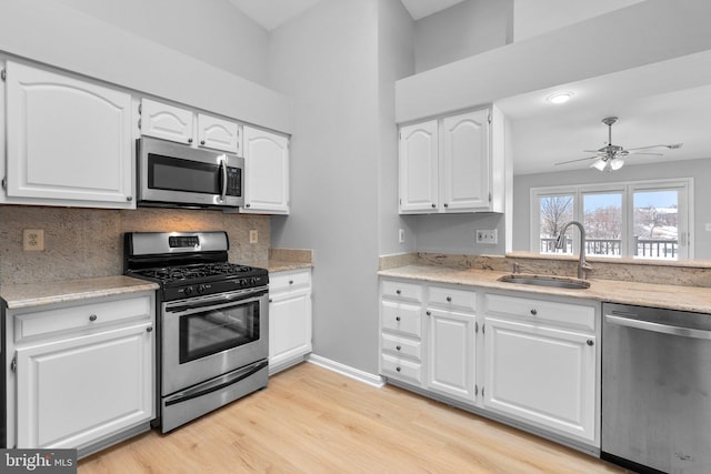 kitchen featuring sink, decorative backsplash, stainless steel appliances, and white cabinets