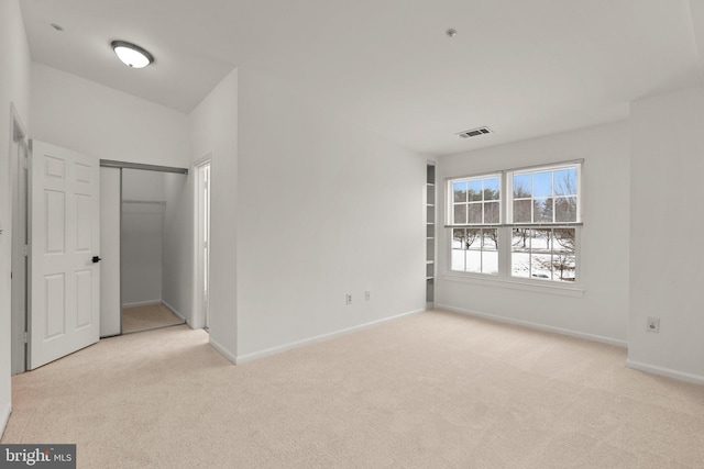 unfurnished bedroom featuring light carpet and a closet