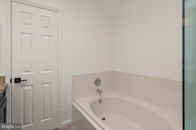 bathroom with vanity and a relaxing tiled tub