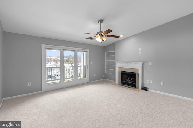 unfurnished living room with light colored carpet, ceiling fan, and built in shelves