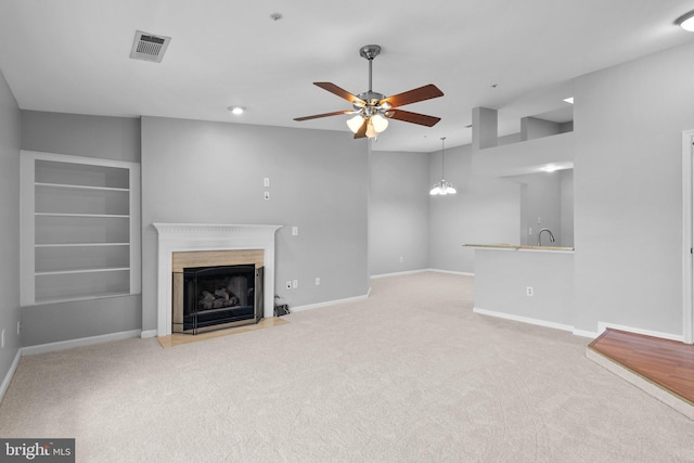 unfurnished living room featuring light colored carpet, sink, and ceiling fan with notable chandelier