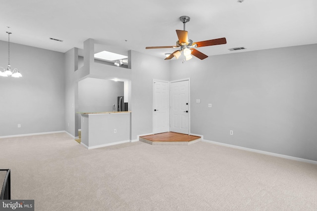 unfurnished living room featuring ceiling fan with notable chandelier and light colored carpet