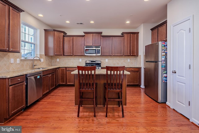 kitchen featuring appliances with stainless steel finishes, a breakfast bar, a kitchen island, and light stone counters