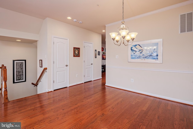 spare room featuring a notable chandelier, crown molding, and dark hardwood / wood-style floors