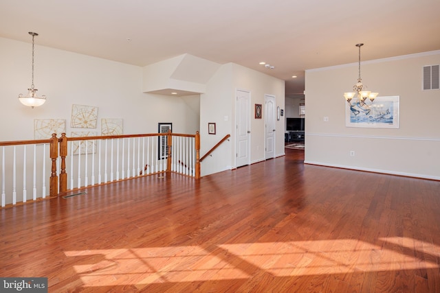 spare room with ornamental molding, hardwood / wood-style floors, and an inviting chandelier