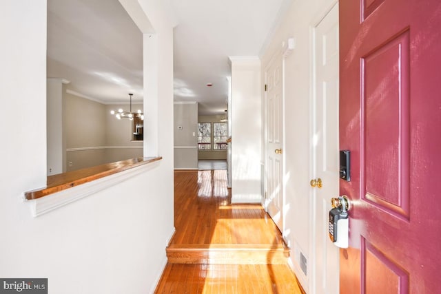 entryway with ornamental molding, hardwood / wood-style floors, and a notable chandelier