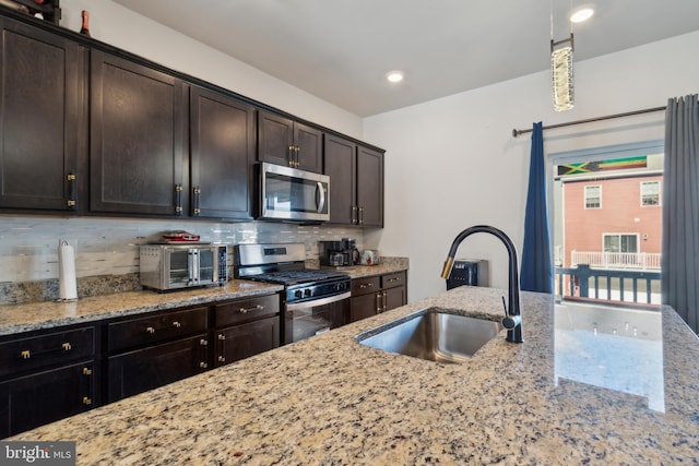 kitchen with stainless steel appliances, light stone countertops, sink, and dark brown cabinets