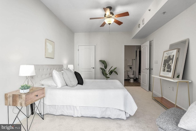 bedroom featuring light colored carpet, ceiling fan, and ensuite bathroom