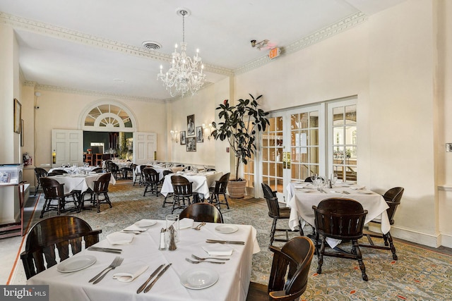 dining area with crown molding, french doors, a chandelier, and a high ceiling