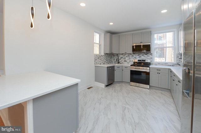 kitchen featuring sink, gray cabinets, backsplash, stainless steel appliances, and kitchen peninsula