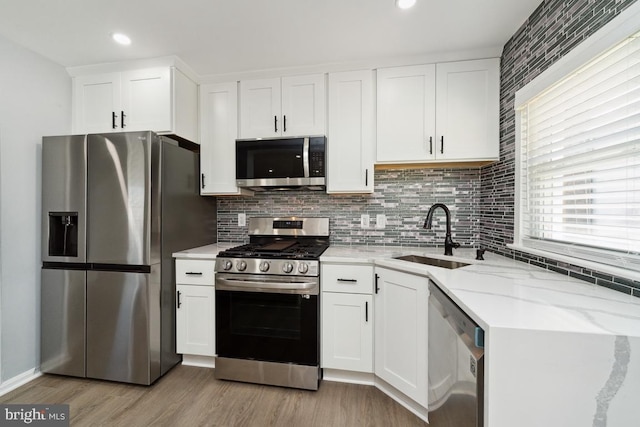 kitchen featuring white cabinetry, sink, light stone counters, and stainless steel appliances