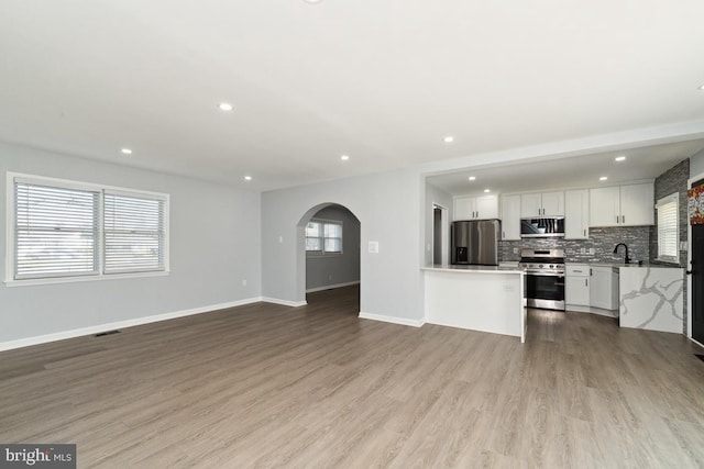 kitchen with sink, stainless steel appliances, light hardwood / wood-style floors, white cabinets, and decorative backsplash