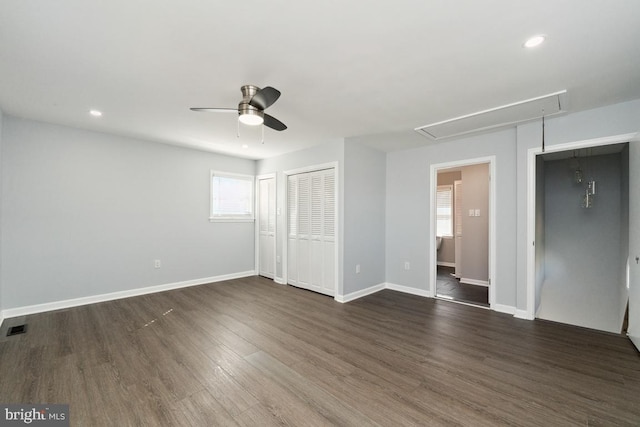 unfurnished bedroom featuring dark hardwood / wood-style flooring, multiple closets, and ceiling fan