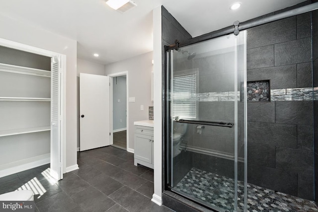 bathroom with walk in shower, vanity, toilet, and tile patterned flooring