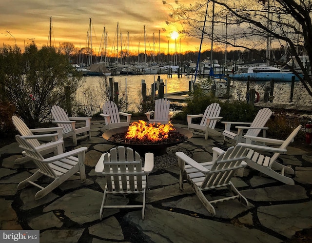 patio terrace at dusk with a water view and a fire pit