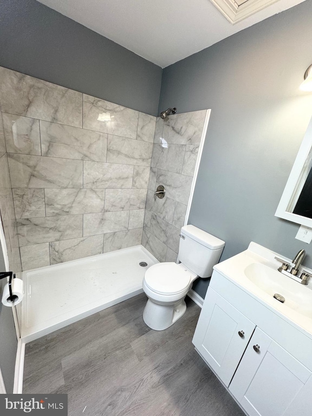 bathroom with vanity, tiled shower, hardwood / wood-style floors, and toilet