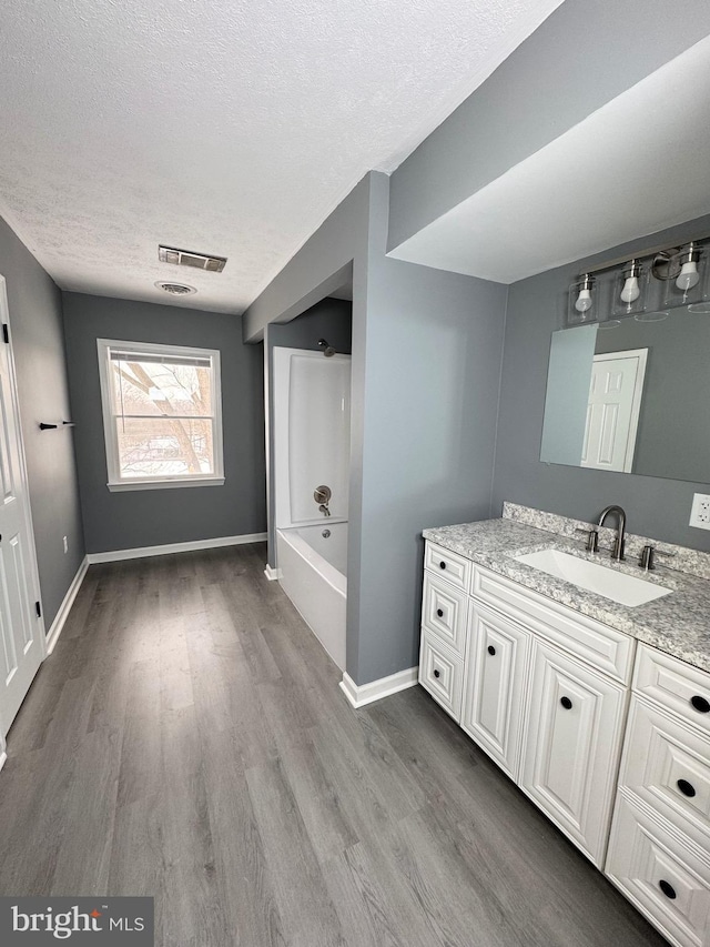 bathroom featuring shower / washtub combination, hardwood / wood-style floors, a textured ceiling, and vanity