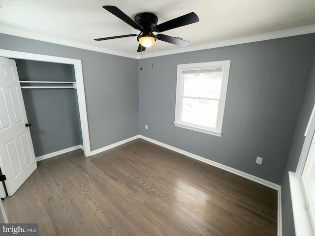 unfurnished bedroom featuring crown molding, dark wood-type flooring, ceiling fan, and a closet