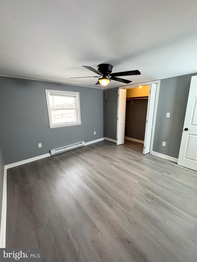 unfurnished bedroom featuring baseboard heating, ceiling fan, and light hardwood / wood-style floors