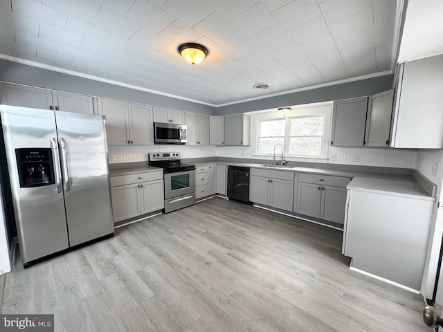 kitchen with sink, gray cabinetry, light hardwood / wood-style floors, stainless steel appliances, and crown molding