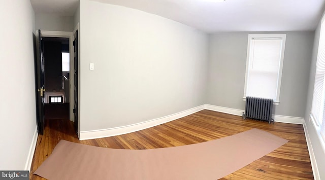 empty room with hardwood / wood-style floors and radiator heating unit