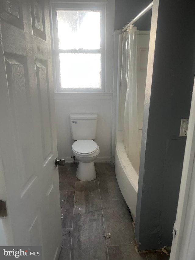 bathroom with shower / bathtub combination with curtain and toilet