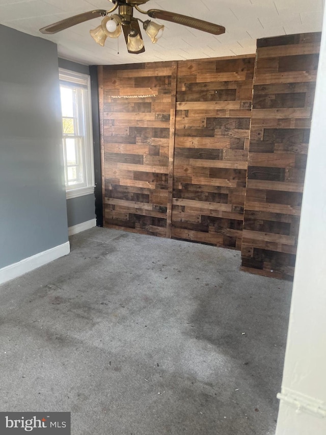 unfurnished room with ceiling fan, carpet floors, and wood walls