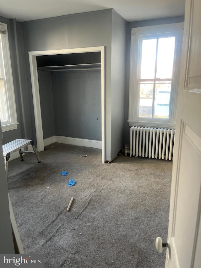 unfurnished bedroom featuring radiator and a closet