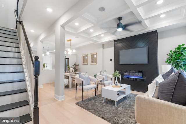 living room with crown molding, light hardwood / wood-style flooring, beam ceiling, coffered ceiling, and ceiling fan with notable chandelier