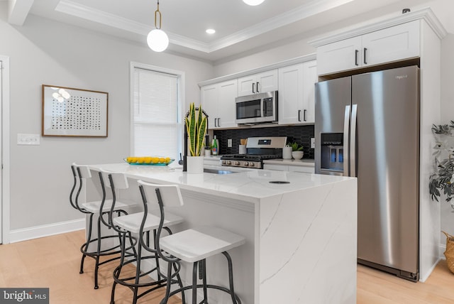 kitchen featuring white cabinetry, appliances with stainless steel finishes, a center island with sink, and decorative light fixtures