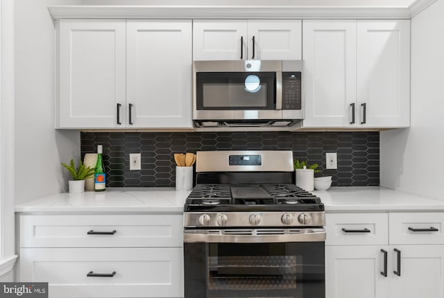 kitchen with stainless steel appliances, white cabinetry, and decorative backsplash