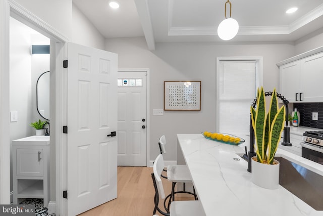 interior space featuring light stone counters, tasteful backsplash, white cabinetry, hanging light fixtures, and light hardwood / wood-style flooring