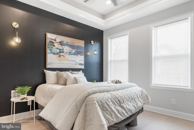 bedroom featuring a tray ceiling and light hardwood / wood-style flooring