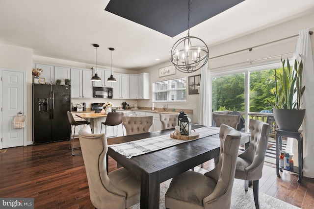 dining area with dark hardwood / wood-style floors, sink, and an inviting chandelier