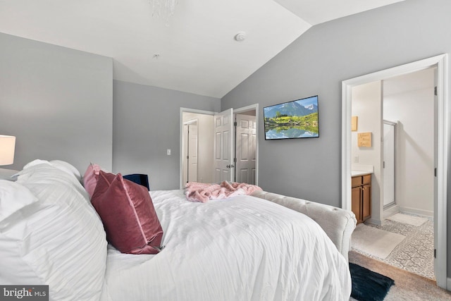 bedroom featuring ensuite bath, vaulted ceiling, and light carpet