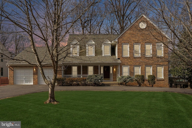 view of front of property featuring a garage, aphalt driveway, a front yard, and brick siding